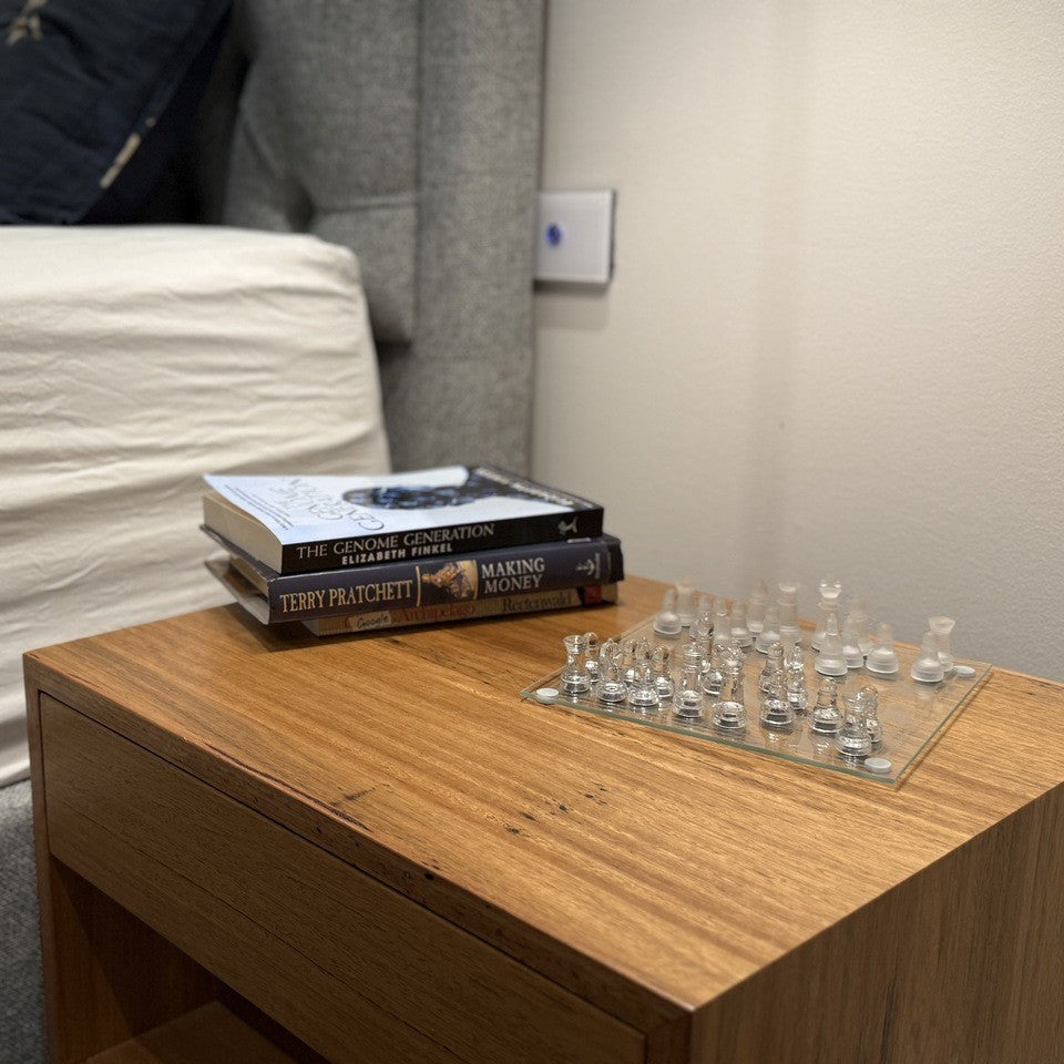 Mini glass chess set on a night stand